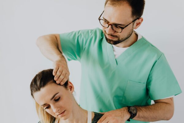 A chiropractor adjusts a patient's neck to relieve pain indoors.